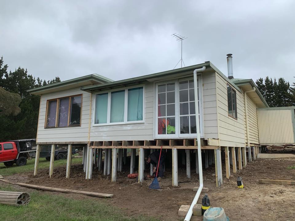 Weatherboard home jacked up on temporary supports during reblocking